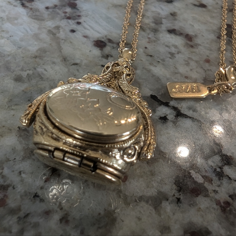 This elegant 1928 Jewelry gold-tone locket features a beautiful three-sided spin